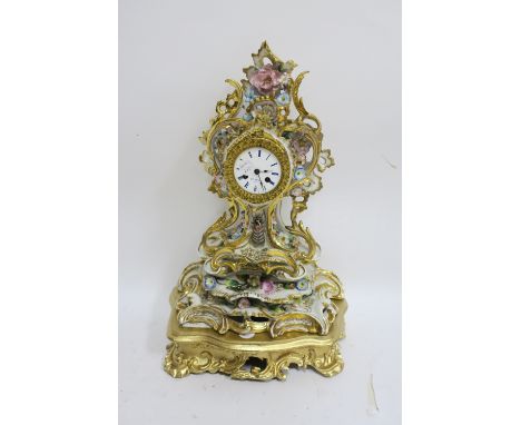 A FRENCH GLAZED PORCELAIN MANTLE CLOCK the profusely scrolled frame with gilded highlights and applied with coloured flower h