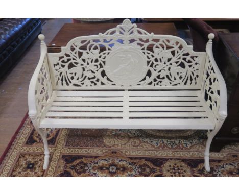 A CREAM PAINTED CAST IRON GARDEN BENCH, the rectangular shield shaped open work back centred by a classical medallion with sh