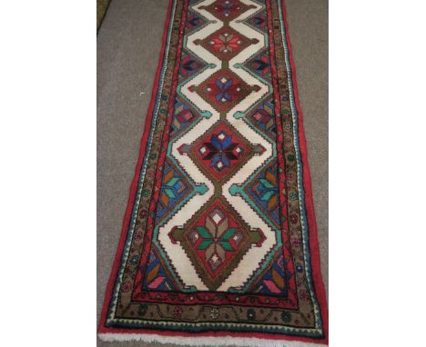 A PERSIAN MESHKIN RUNNER, the light pink beige and green ground with central panels with stylised foliage within a conforming