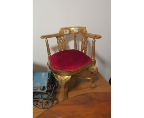 A MINIATURE MODEL OF A GEORGIAN GILT CORNER CHAIR, with red upholstered seat on cabriole legs with claw and ball feet.