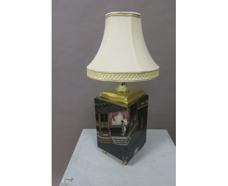 AN ORIENTAL STYLE TABLE LAMP, the cream shade above a rectangular base decorated with figures and street scenes, on brass bun