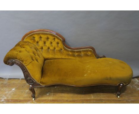 A VICTORIAN MAHOGANY CARVED CHAISE-LONGUE the scrolled and foliate carved frame with shaped button upholstered back and side 