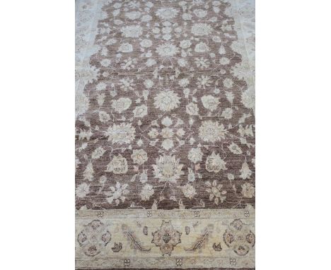 A WOOL RUG light brown with beige field with central floral panel within a conforming border 240cm X 170cm 