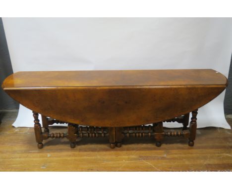 A 20TH CENTURY WALNUT VENEERED HUNT TABLE the plain top with moulded rim raised on ring turned and blockend gate leg supports