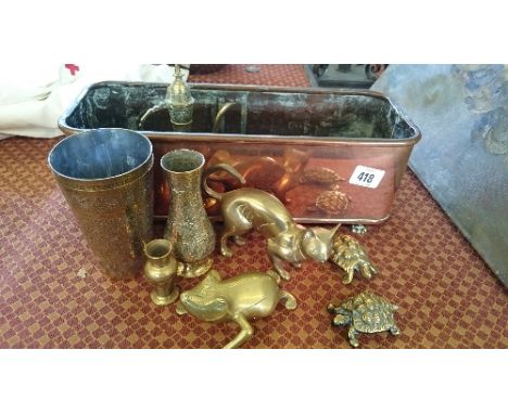 A copper flower trough containing various brass ornaments. 