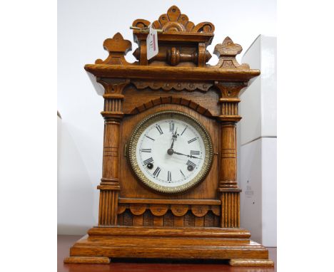 A late 19th century oak cased mantel clock having an enamel dial with Roman numerals and eight day movement striking on a gon