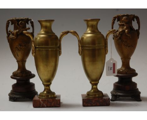 A pair of Art Deco gilt brass twin handled clock garniture urns, each raised on square rouge marble plinth, h.23cm, together 