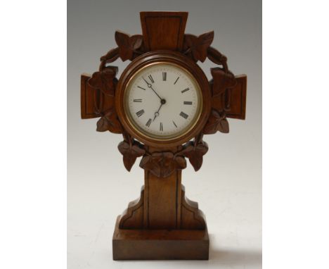 A late Victorian oak cased mantel clock, the enamelled dial with Roman numerals, the case in the form of a cross with carved 