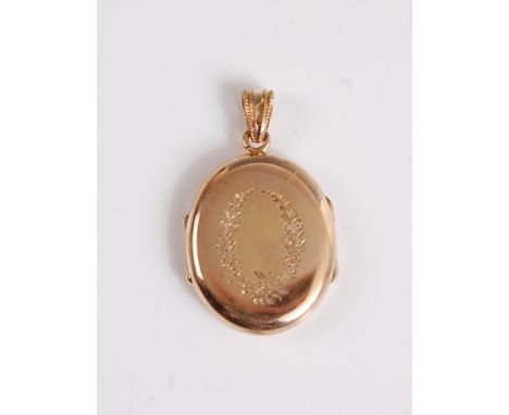 An unmarked oval yellow metal locket, with floral engraved decoration to both sides and interior hinged glazed panel, with ta