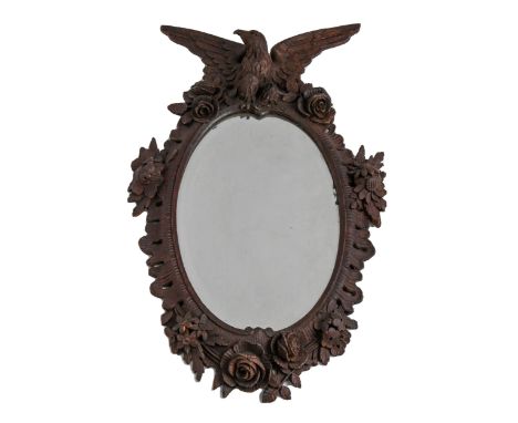A German carved and stained wood oval mirror, late 19th c,&nbsp; crested by an eagle in a rococo surround with roses and othe