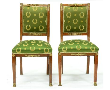 A pair of Charles X ormolu mounted mahogany chairs, with padded back,&nbsp; in Empire style green laurel pattern silk, the fo