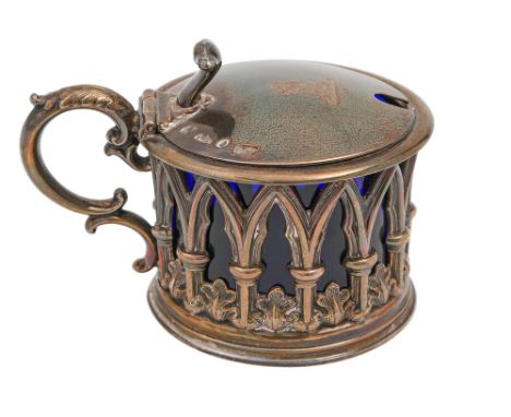 A Victorian gothic silver mustard pot, the sides pierced with arches and water leaves, crested, blue glass liner, 70mm h, by 