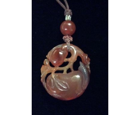AN ANTIQUE ORIENTAL RED JADE AND SEED PEARL PENDANT  Carved with an exotic fruit with pierced gnarled branches, capped with a