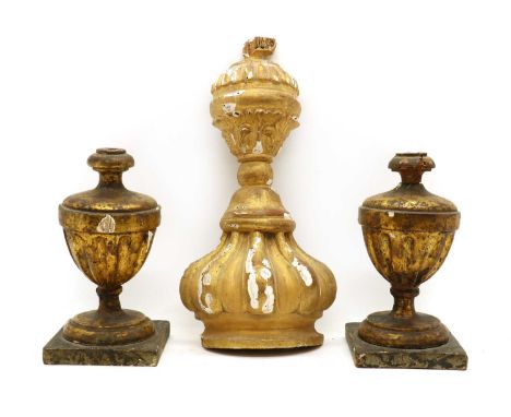 A group of three carved giltwood ornaments,early 20th century, comprising a pair of urn form bannister finials, 24cm high, an