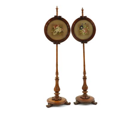 A pair of Victorian walnut pole screens,the adjustable circular screens, inset with tapestry foliate panels, raised on a carv