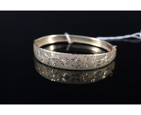 A 9ct gold bangle with matte effect finish and engraved foliate decoration, weight approx 9.5g