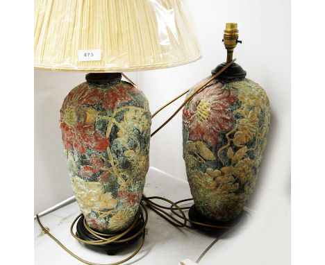 A pair of ceramic table lamps, decorated with flowers and foliage in shades of gilt and red, on a background, each raised on 