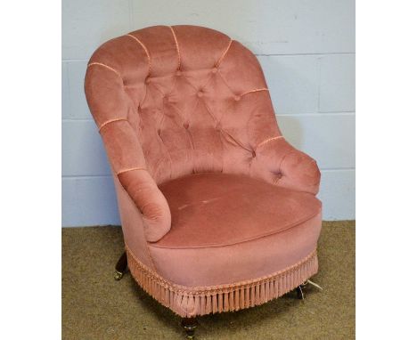 A Victorian button-back nursing chair, upholstered in pink velour, on squat turned legs with brass castors, 63 x 69 x 81cms h
