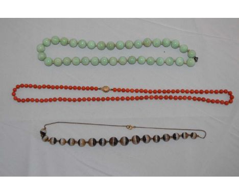 A late 19th/early 20th Century banded agate bead necklace, on plated chain; a red coral bead necklace, the clasp stamped '9kt