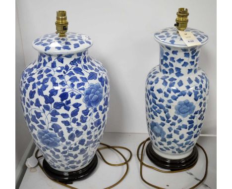 Two Chinese blue and white ceramic table lamps, of various shapes, each raised on a stepped, stained wood circular base, the 