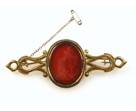 Victorian yellow metal (assayed 9ct) fancy 'scroll' open work bar brooch, featuring at centre a bezel set oval intaglio of en