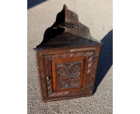 19th Century Flemish carved oak corner cupboard with shaped gallery and shelf above, floral panelled door, on a plinth base, 