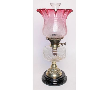 A Victorian oil lamp by Veritas with etched and crimped cranberry glass shade, cut glass reservoir, brass pedestal and potter