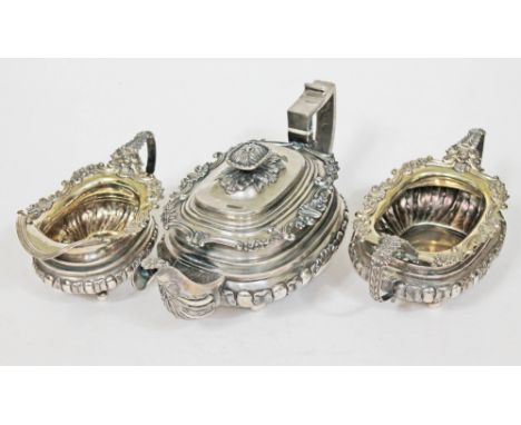 A George IV three piece silver tea set, floral and shell borders and handles and embossed gadrooned leaf decoration to body, 