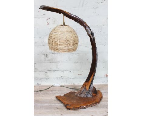 A retro table lamp naturalistically formed with in yew wood with suspended woven shade, height 70cm.  