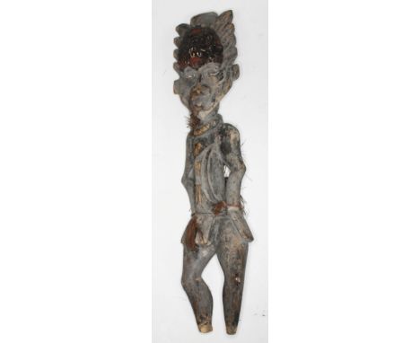 A carved ethic figure form as a man standing wearing a head dress adorned with cowrie shells and having cowrie shell eyes, le