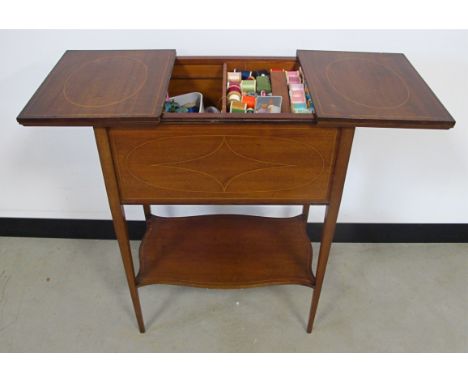 A mahogany inlaid sewing box on stand, having side open split top to reveal contents of sewing equipment and threads, on long