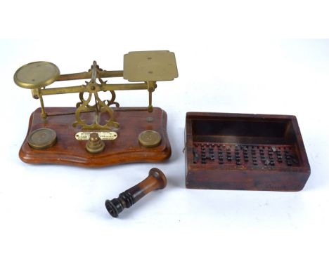 A set of early 20th Century brass postal scales, set on a wooden base with weights, together with a set of date blocks and a 