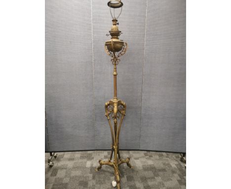 An Edwardian tall brass standard lamp,with ornate supports and decoration, converted and for decorative purposes only, height