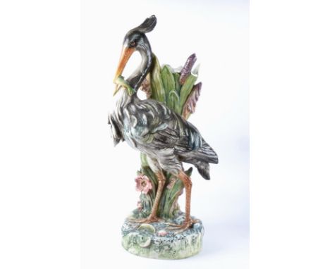 A Continental pottery stick or umbrella stand c1900 taking the form of a heron eating a fish,  height 81cm, AF with damage to