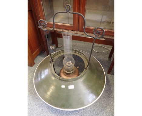 A GREEN ENAMEL LAMPSHADE with cast iron hanging and brass oil lamp to the interior (on view at Fine Art)