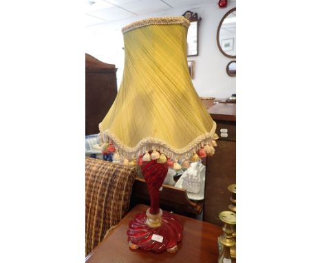 A RED ART GLASS TABLE LAMP of spiraled tapering form, on gold bun feet, 39cms high (on view at Fine Art)