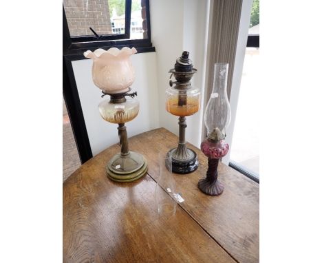 A CONVERTED TABLE OIL LAMP with a pink glass floral shade and two further table lamps (on view at Fine Art)