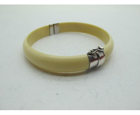 An Early XX Century Plain Ivory Bangle, with stamped Silver hinge and fastener 6.5cm diameter.