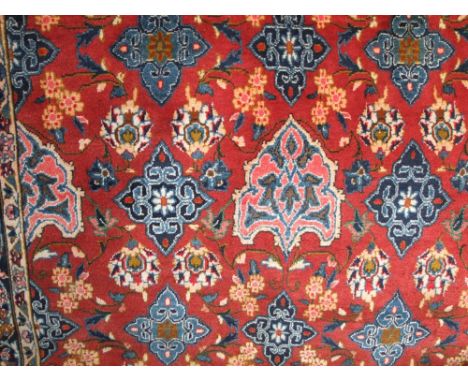 An eastern style wool carpet with red ground field, multi floral panels, set within running borders, 320cm x 200cm 