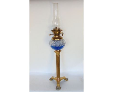 Brass corinthium column oil lamp with star cut glass reservoir upon a triform plateau and paw feet, the lamp 61 cm high 