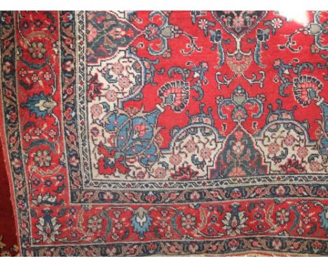 An eastern wool red ground carpet with central medallion, further geometric detail set within running borders, 190cm x 140cm 