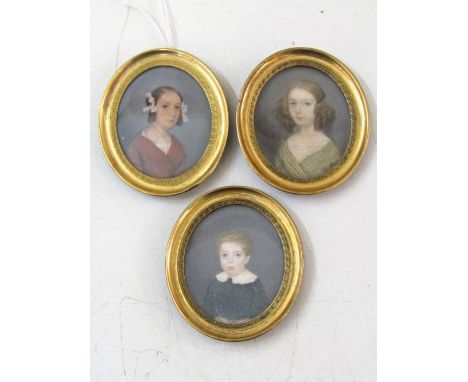 A set of three 19th century bust length portrait miniatures of oval form showing two girls and a boy, 4cm max, in gilt metal 