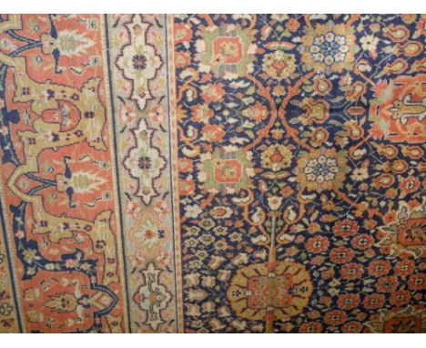 A Wilton carpet in a Persian style, with dark blue field, multi floral detail and set within running borders, 450cm x 270cm a