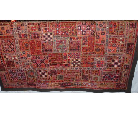 An Indian wall hanging/bed spread with colourful patchwork of embroidery and mirror work and black border, 191 x 144 cm