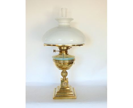 A late 19th century brass and vaseline glass oil lamp with opaque glass shade and stepped square base with applied flower hea