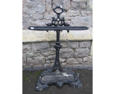 A cast iron stick stand with pierced back, shaped tray and central carrying handle