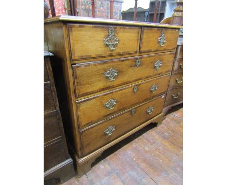 A late Georgian oak chest of three long and two short drawers, cross banded in walnut with cast brass fittings on bracket sup