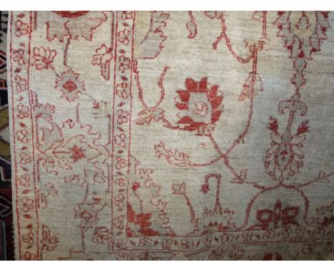 A Persian style wool carpet with cream ground field and abstract floral detail in a red colourway, 240cm x 155cm