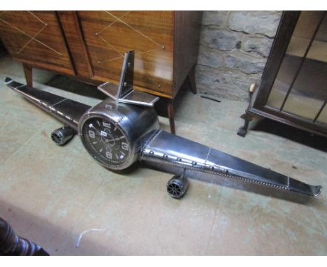 A contemporary novelty wall clock in the form of an aircraft nose cone with simulated pop riveted seams to wings and framewor