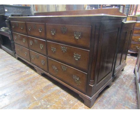 A Georgian oak Lancashire fitted with an arrangement of nine frieze drawers, cross banded in walnut with brass fittings, with